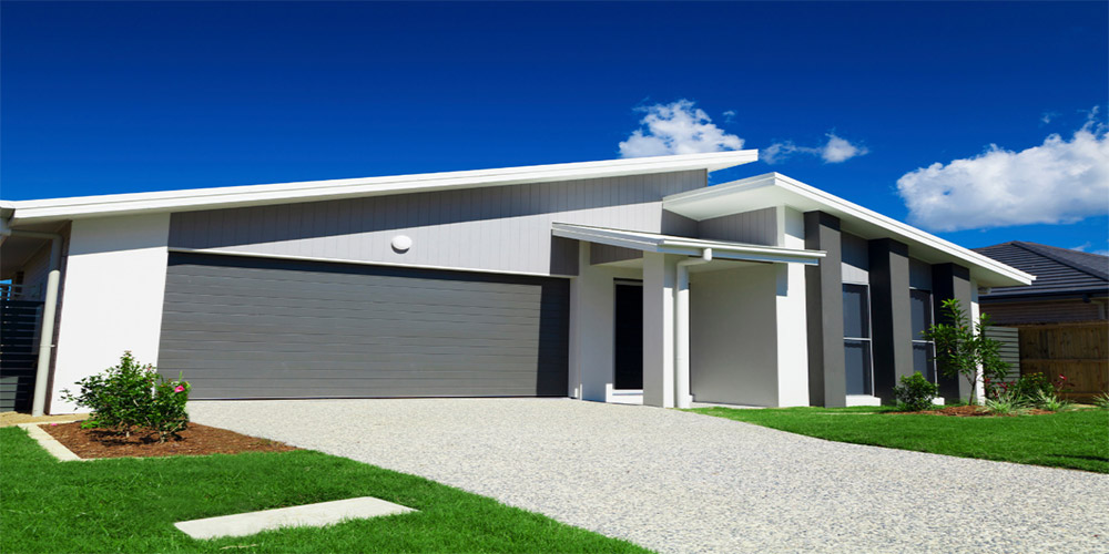 A modern house with a garage and a lawn under a blue sky.